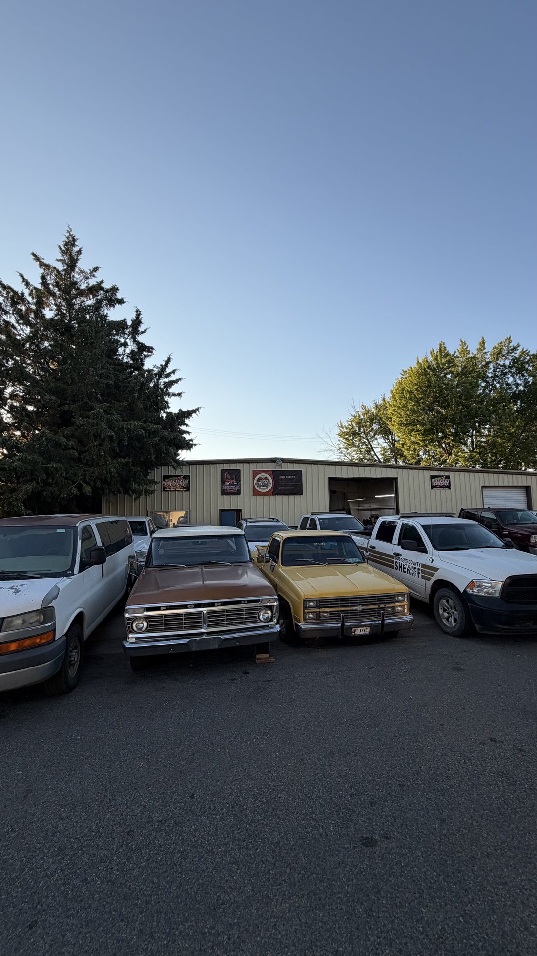 High Desert Auto & Repair shop exterior at dusk with customer vehicles